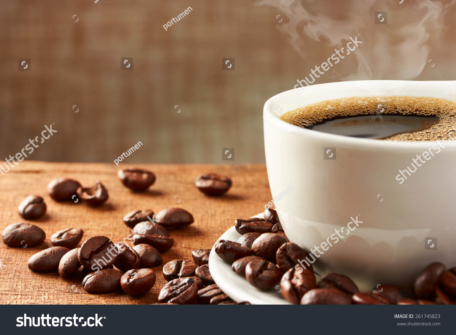 A cup of coffee surrounded by roasted coffee beans
